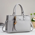 Close-up of light grey lychee pattern leather tote bag with silver lock and decorative charm - Gray
