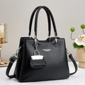 Detail of black litchi leather tote bag with elegant logo and mini charm accessory - Black
