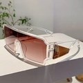 Detalle de gafas de sol futuristas con lentes degradadas marrones en un pedestal blanco - Marco Transparente Lentes Té Degradado