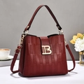 Close-up of burgundy leather handbag with vertical embossed texture and gold metal clasp - Wine Red