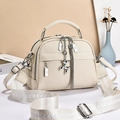 Détail du sac à main en cuir beige avec large bandoulière à motifs et pendentifs décoratifs - Blanc Cassé