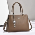 Detailed texture of dark brown pebbled leather handbag with flower charm and strap - Coffee