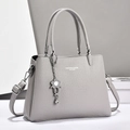 Elegant grey litchi grain leather handbag with top handles and a flower pendant charm - Gray