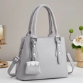 Détail du sac cabas gris clair grainé avec doubles anses et breloque chaîne en métal - Gris