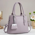 Détail du sac à main en cuir grainé lilas avec ferrures argentées et mini accessoire - Violet