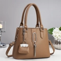 Elegant brown pebbled leather tote bag with silver hardware and tassel charm on white desk - Khaki