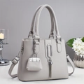 Detail of light gray lychee grain leather handbag with silver rings and mini bag charm - Gray