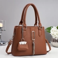 Detailansicht einer braunen Lederhandtasche mit Silberquaste und Mini-Münzgeldbörse - Erdgelb