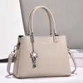 Dettaglio della borsa tote beige con trama in pelle martellata e ciondolo floreale argento - Cachi Chiaro