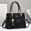 Close-up of black leather tote with silver buckle and flower pendant detail - Black