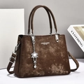 Detail of dark brown vintage textured handbag with metallic flower charm and strap - Coffee