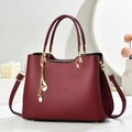 Burgunderrote Handtasche aus Leder mit goldener Hardware und Quastenanhänger-Detail - Weinrot
