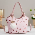 Pink bucket bag with cherry print and bow charm on a decorative vintage background - Pink