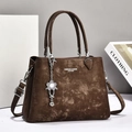 Close-up of dark brown leather handbag with vintage texture and silver flower charm - Coffee