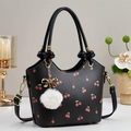 Detail of black bucket bag with cherry print, gold hardware, and white plush charm - Black