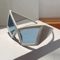 Close-up of geometric oversized cream sunglasses with translucent blue lenses and sharp edges - Grey Frame Blue Lens