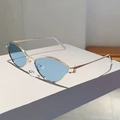 Detail view of cat-eye sunglasses with gold metal frame and light blue transparent lenses - Gold Frame Blue Lenses