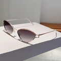 Detail of cat-eye metal sunglasses with gold frame and gradient lenses on a display stand - Gold Frame Gradient Grey Lens