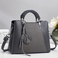 Detail of grey crossbody bag with woven handle, V-shaped stitching and round charm - Gray