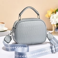 Minimalist light blue handbag with textured pattern and wide woven strap in chic setting - Blue