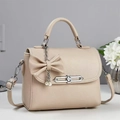 Close-up of beige lychee textured leather bag with silver chain and pearl bow charm - Khaki