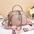 Detail of dusty pink pebbled leather bag with woven strap and silver puppy charm - Pink