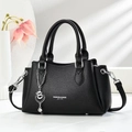 Close-up of black lychee grain leather handbag with silver heart charm and metal feet - Black