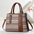 Detail of woven rainbow tote with leather trim and gold rivet accents on white surface - Light Color Wave With Coffee (Coffee 1)