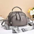 Detailed view of grey pebble leather handbag with wide woven strap and metal hardware - Gray