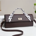 Detail of dark brown leather handbag featuring a polka dot scarf handle and gold twist lock - Coffee