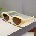 Close-up of retro cat-eye sunglasses with cream frames and brown lenses on a platform - Jelly Yellow Frame Tea Lens