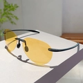 Detalle de gafas de sol de aviador sin montura con lentes ámbar en un pedestal blanco - Montura Negra Lentes Amarillas