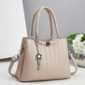 Dettaglio della borsa beige con texture a nido d'ape e ciondolo floreale - Albicocca