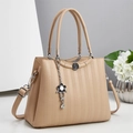 Dettaglio della borsa beige con motivi a nido d'ape e ciondoli a forma di fiore argento - Cachi