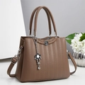 Bolso de mano en cuero marrón con textura tejida y colgante floral, vista de 45 grados - Marrón
