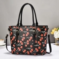Detail of black tote bag with red cherry pattern, gold hardware and leather texture - Black
