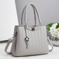 Bolso de mano gris claro con textura granulada, colgante floral y detalles plateados - Gris