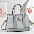 Classic grey tote bag with pleated texture and golden logo in a stylish room setting - Gray