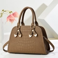 Brown crocodile embossed tote bag with gold hardware and heart charm on white podium - Brown