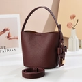 Close-up of burgundy bucket bag featuring textured leather, bow knot, and gold padlock - Wine Red