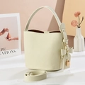 Elegant beige bucket bag with litchi texture and bow charm on a minimalist background - Off White