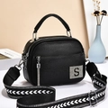 Minimalist black lychee pattern crossbody bag with wide strap and tassel in a clean room - Black