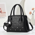 Dettaglio macro della borsa in pelle nera trapuntata con strass e ciondolo a cuore - Nero