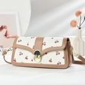 Bolso de hombro con estampado de cerezas, borde marrón y cierre dorado sobre fondo minimalista - Caqui (Estampado de Cerezas)