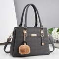 Vue détaillée du sac à main gris motif crocodile avec plaque dorée et pompon beige doux - Gris