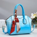 Detail van lichtblauwe handtas met krokodillenpatroon, zijden sjaal en goudkleurige details - Blauw