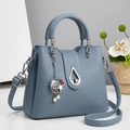 Detailed view of Morandi blue lychee leather bucket bag with silver drop buckle and charms - Morandi Blue