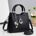 Detalle de bolso de cuero granulado negro con colgante de concha y cierre metálico de gota - Negro