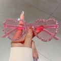Close-up of pink heart-shaped rimless sunglasses featuring sparkling crystals on frames - Pink