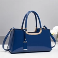 Detail of navy blue patent leather handbag with gold U-shaped hardware and orchid accent - Blue
